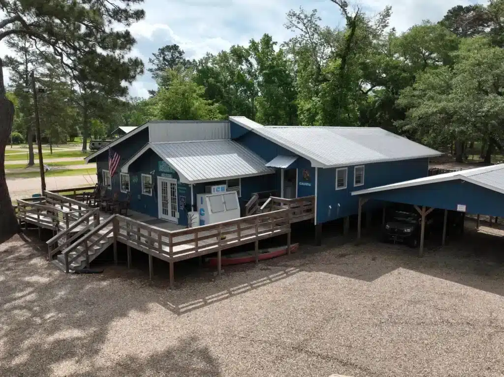 Aerial view of a blue camp store and office building with wooden decks, ramps, ice machines, and covered parking.